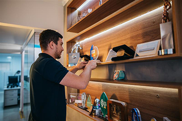 Homem organizando prêmios de reconhecimento em prateleiras.