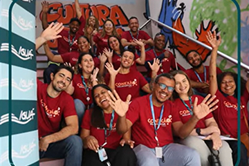 Colaboradores da Iguá reunidos em uma ação social, sorrindo e acenando para a câmera.