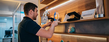 Imagem de um homem colocando um troféu em uma prateleira